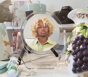 round mirror on table showing woman with curly blonde hair